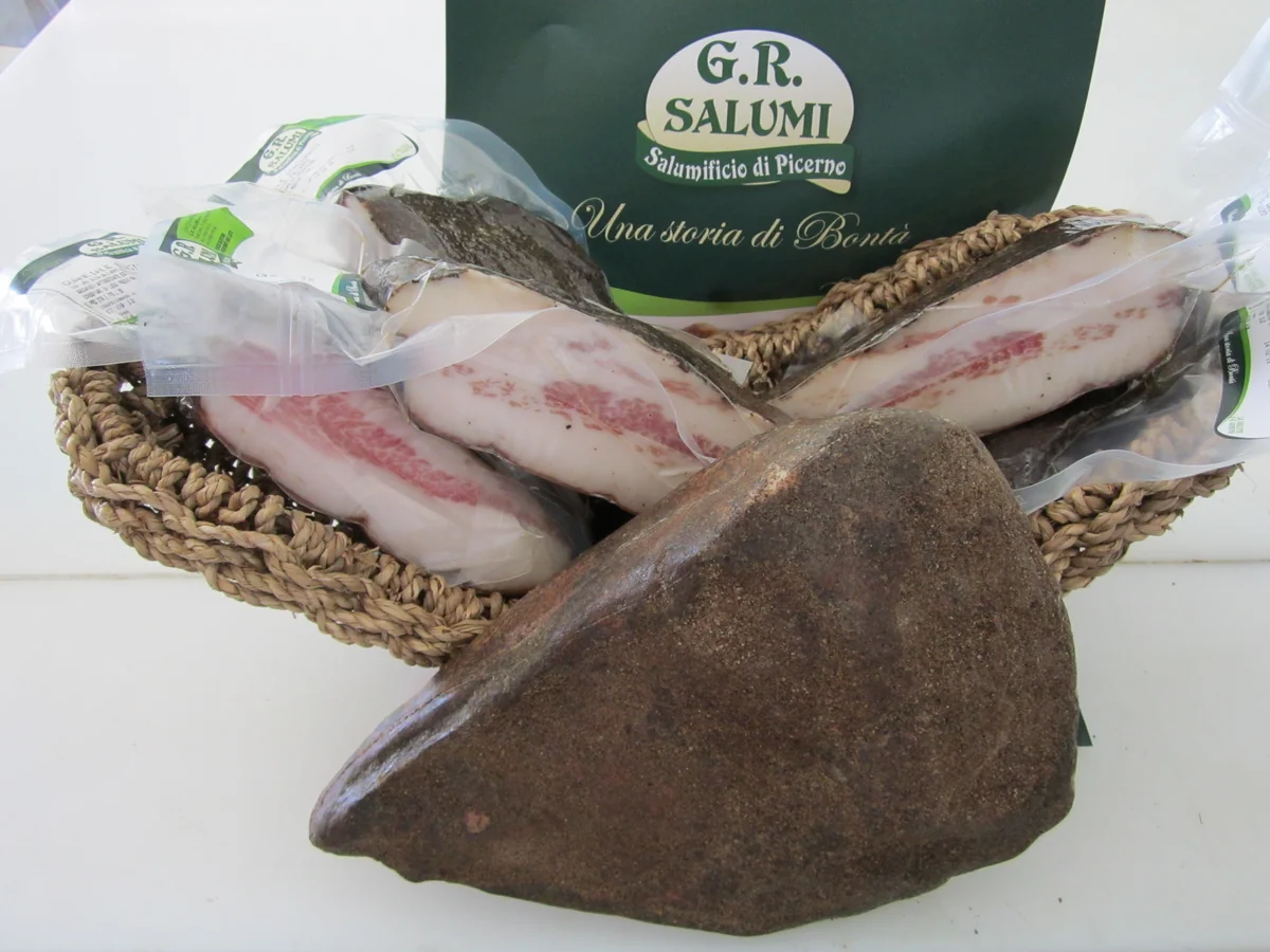 Guanciale intero e porzionato, con confezioni G.R. Salumi in un cesto.