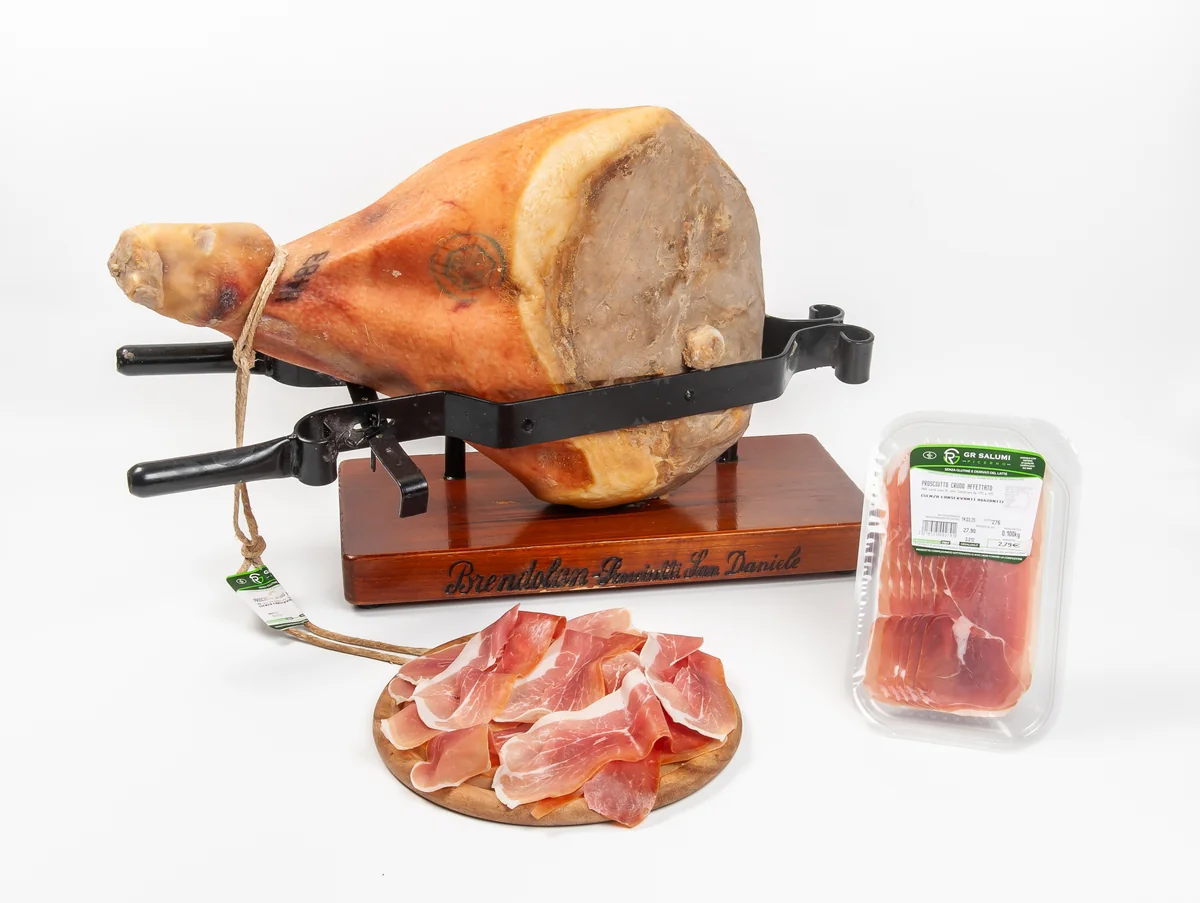 Prosciutto crudo intero su morsa, fette e confezione G.R. Salumi su fondo bianco.