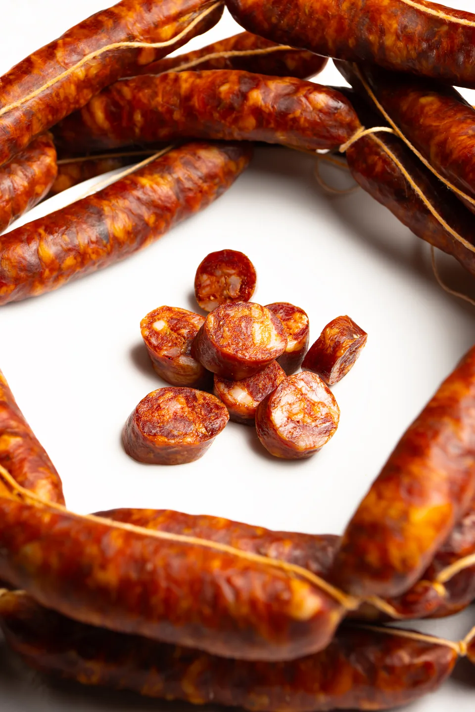 Salsiccia intera e tagliata a bocconcini su un piatto bianco.